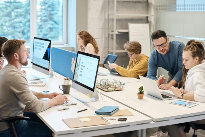 Interior of a modern office with computers and a team sitting at their desks working