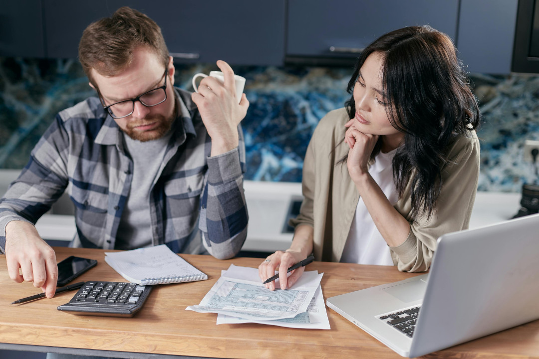 Photo of a man and a woman sitting at a desk in an office environment looking at documents
