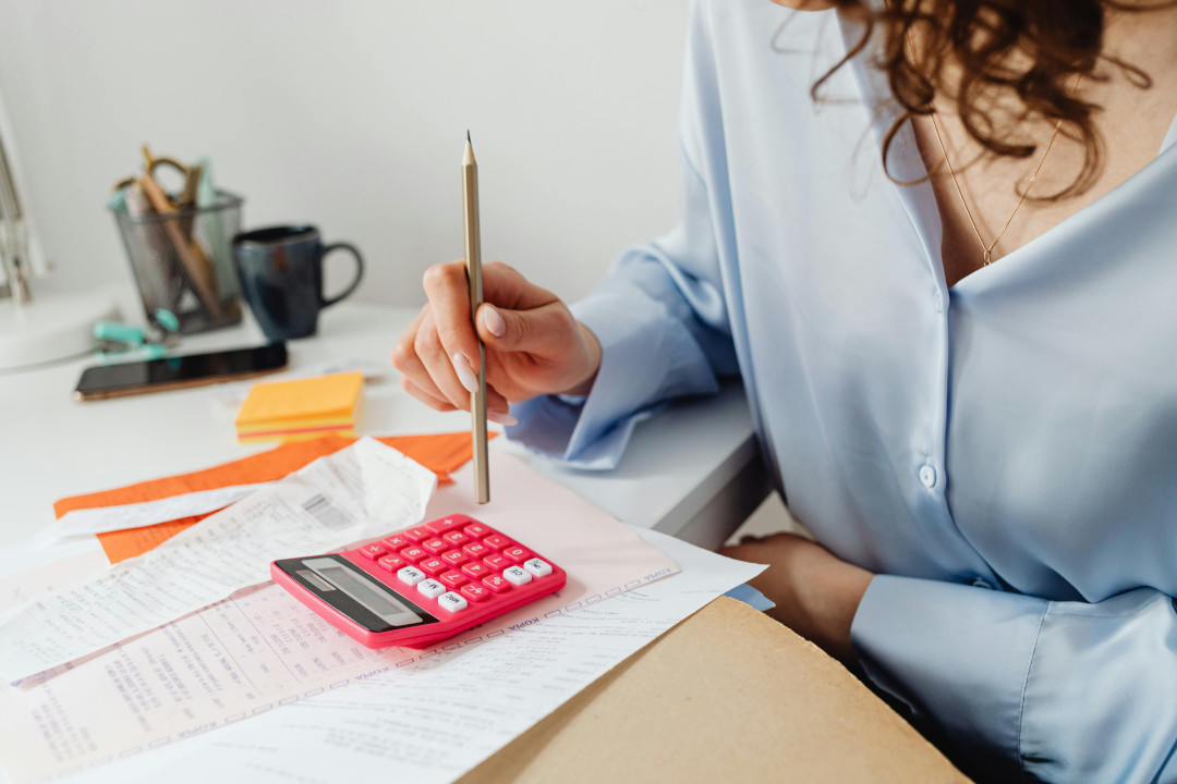 Photo of a woman focusing on her hands, sitting in an office looking through documents holding a pencil