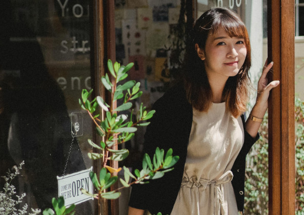 Young woman next to an open sign infront of a shop in Oxford, UK