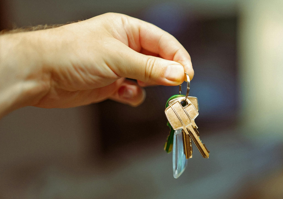 Set of office keys being handed over with a modern office interior in the background