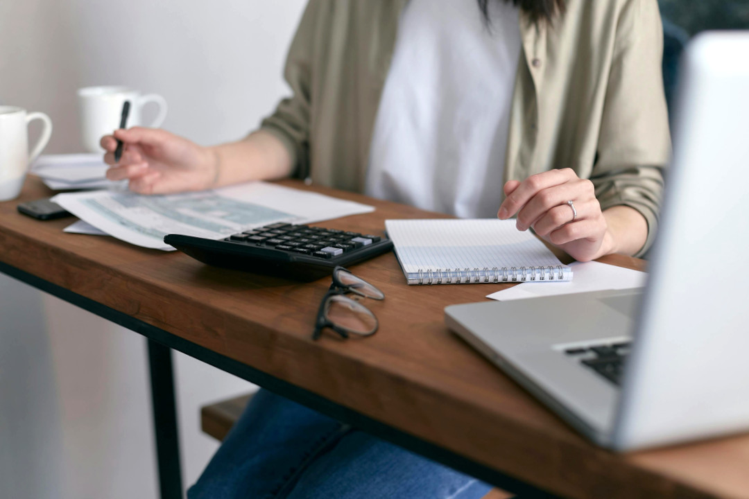 Photo of a woman sat and a desk with corporate paperwork, files, and legal documents used in company secretarial management