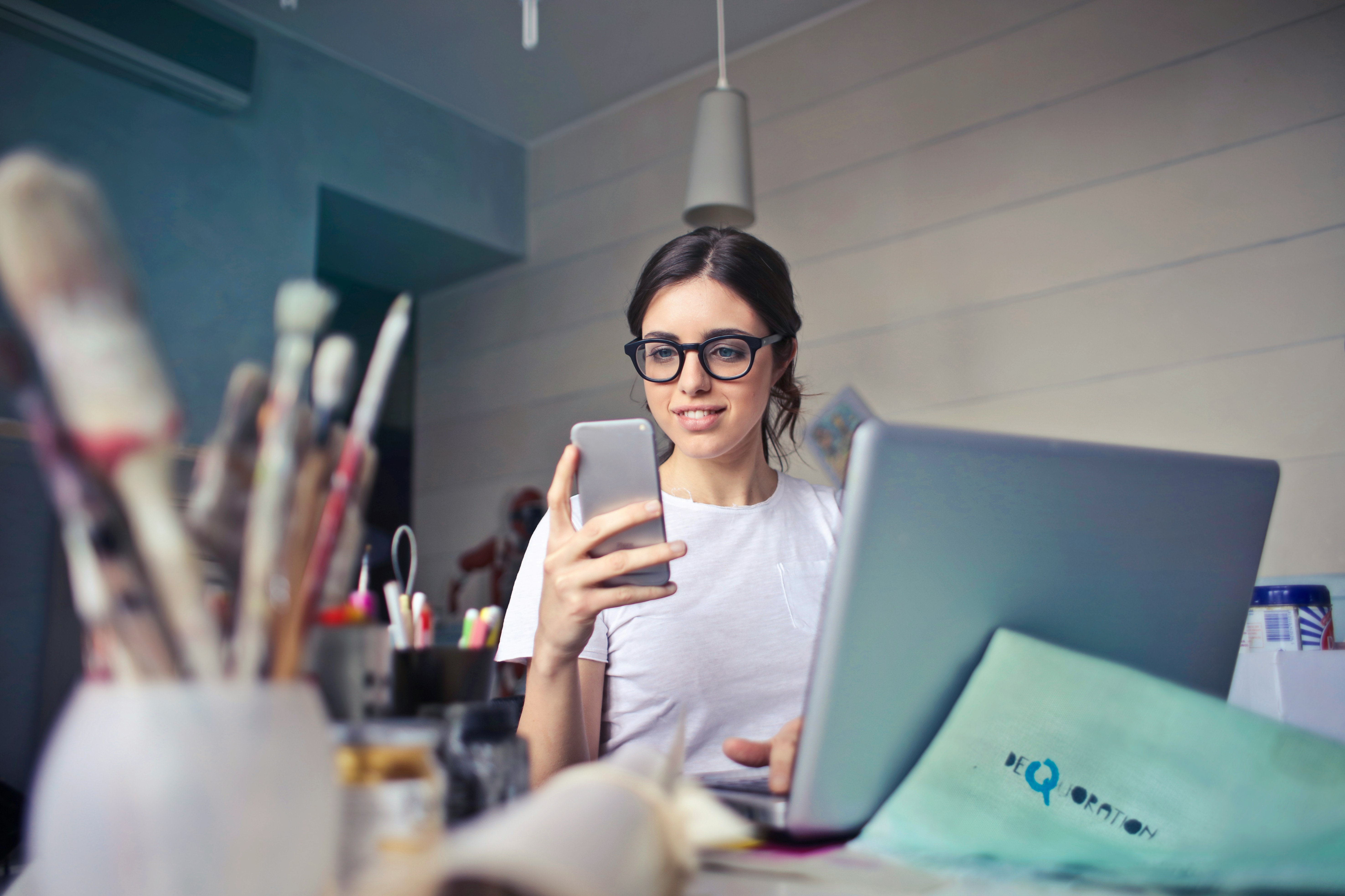 Image of a young woman at a creative studio completing her self-assessment on a mobile phone
